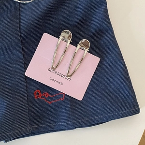 Détail de pinces à cheveux goutte en métal argenté poli sur carte rose et denim