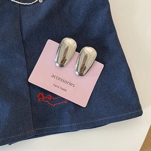 Détail de pinces à cheveux argentées en forme de haricot sur carte rose et tissu