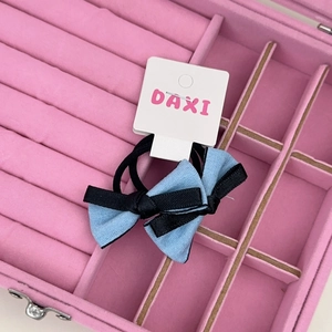 Détail de barrettes à nœud bleu et noir sur carte blanche dans un écrin en velours rose