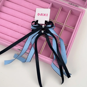 Détail des barrettes à nœud ruban bleu et noir avec perles argentées sur velours
