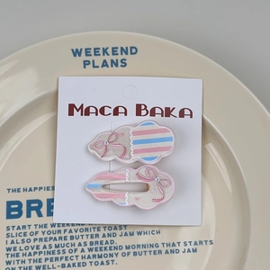Detail of floral cloud-shaped hair clips with pink bows on a ceramic display tray