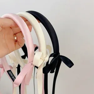 Elegant satin bow headband with long ribbons in pink, white, and black colors