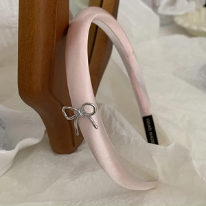 Close-up of pink satin headband with silver bow detail and hand made label