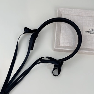 Detail of black satin headband featuring elegant long ribbon streamers in French style