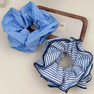 Detail view of large striped scrunchies in blue and white fabric on a wooden tray
