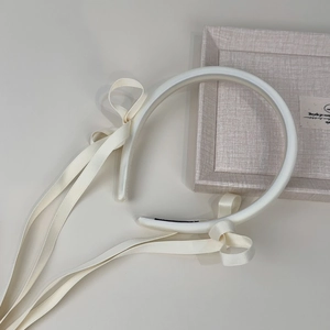 Detail view of cream white satin padded headband with elegant long ribbon streamers