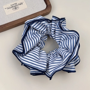 Close-up of blue and white striped fabric scrunchie with navy blue piping detail