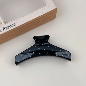Detail of a large French style black and white polka dot hair claw clip with glossy finish