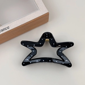 Detail of star-shaped hair claw clip with black and white polka dots and gold spring