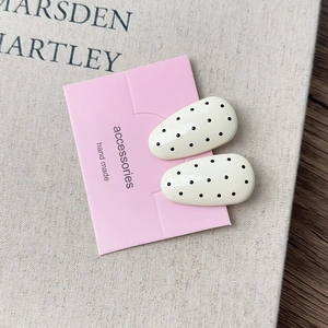 Detail of French style black polka dot clips on a pink card on a rustic wooden desk