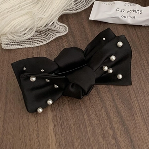 Barrette élégante en satin noir avec perles blanches sur une surface en bois