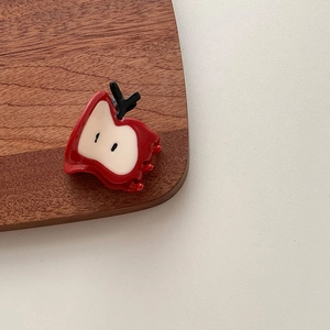 Détail d'une pince à cheveux pomme rouge montrant la finition résine et les graines