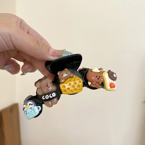 Vue détaillée de la pince à cheveux noire avec ours 3D, fromage et pain grillé décoratifs