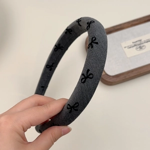 Detailed texture of gray padded headband with black bow patterns and soft knit fabric
