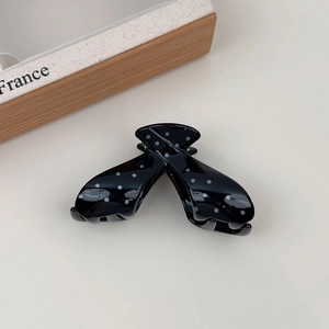 Detail of French style black and white polka dot hair claw clip on neutral background