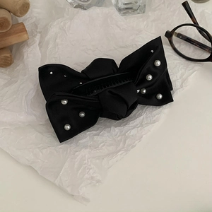 Détail d'une pince banane en satin noir avec perles élégantes et lunettes en écaille