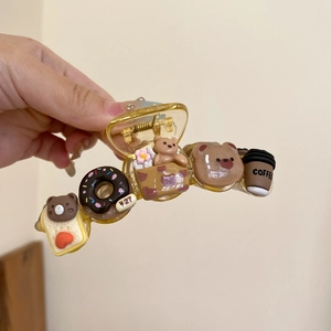 Détail d'une pince à cheveux jaune avec des breloques de d'ours et de tasse à café mignons