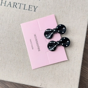 Detail of black and white polka dot bow hair clips on pink handmade display card