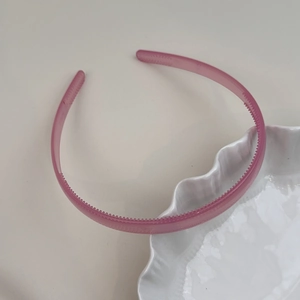 Détail d'un serre-tête rose translucide avec fines dents antidérapantes et design mince