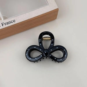 Detailed view of a black hair claw clip with white polka dots and a golden spring mechanism