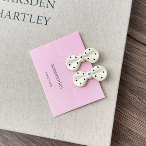 Detailed view of handmade bow hair clips with black polka dots on display card