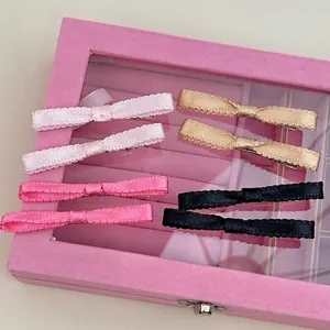 Set of 8 satin ribbon bow hair clips in pink, gold and black on a velvet box lid