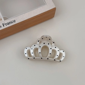 Close-up of crown-shaped hair claw clip in pearl white with black polka dots finish