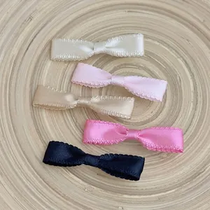 Five-piece set of elegant satin bow hair clips in multiple colors on a wooden tray