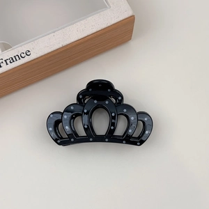 Close-up of crown-shaped black hair claw clip with elegant white polka dots for women