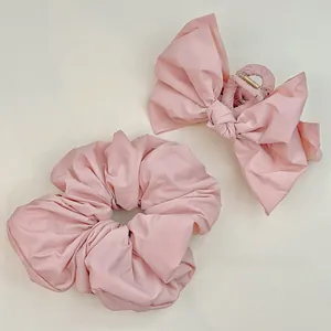 Ensemble pince à cheveux avec nœud rose et chouchou plissé sur fond minimaliste beige