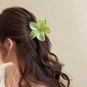 Grüne Plumeria-Haarklammer mit Marmor-Textur, getragen von Model in schlichtem Ambiente