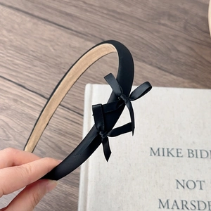 Detail of a thin black fabric headband with double bows and non-slip velvet inner lining