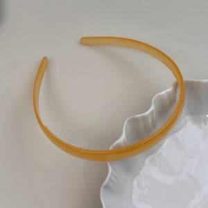 Gros plan d'un serre-tête ambre effet gelée avec dents antidérapantes sur fond blanc pur