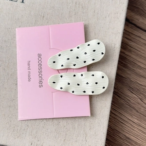 Detail of two French style polka dot hair clips on display card with wave texture