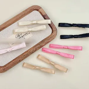 Close-up of colorful silk ribbon bow hair clips in cream, pink, black, and gold colors