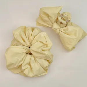 Détail d'un ensemble cheveux en tissu jaune pâle avec pince à nœud et chouchou texturé