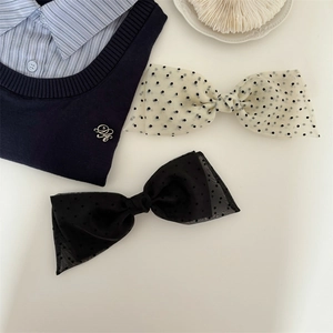 Vintage large polka dot and black tulle bow hair clips set on a striped shirt background