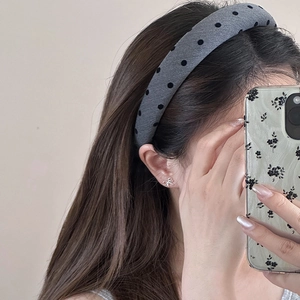 Close-up of a model wearing a grey polka dot headband and silver bow-shaped earrings