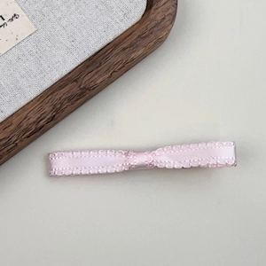 Detailed close-up of pink satin ribbon bow hair clip with textured weave edges