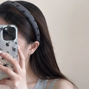 Mirror selfie showing a wide dark grey headband with bow pattern on a model