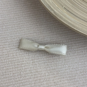 Detailed macro view of a cream satin ribbon hair clip with delicate lace edges