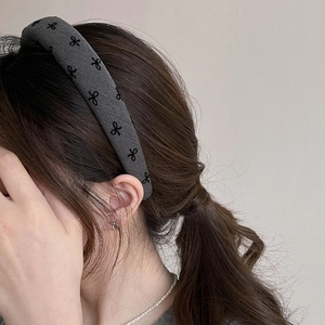 Detail of grey wide headband with black bow patterns on thick knitted fabric material