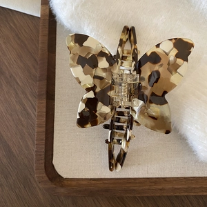 Detailed macro of tortoise shell acetate butterfly hair claw with metal spring on white fur