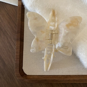 Detail view of pearly marble texture butterfly hair claw clip with gold metal spring