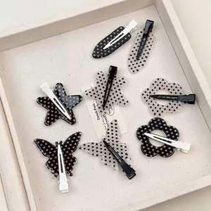 Set di fermagli per capelli a pois in forme di farfalla e stella su vassoio beige