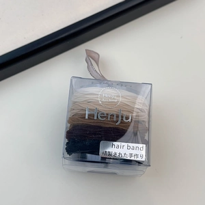 Detail of high-elasticity hair bands set in earth tones inside a clear plastic gift box