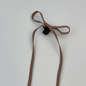Détail d'une pince à cheveux avec nœud en cuir marron et rubans style ballerine chic