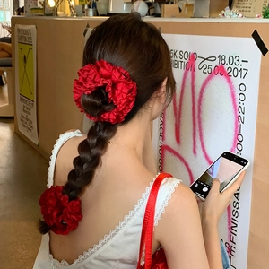 Gros plan de chouchous en satin rouge à volants sur une tresse pour un style chic