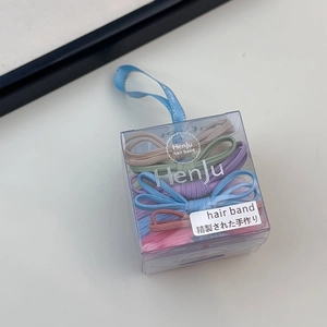 Macro view of assorted pastel bow hair ties organized in a clear plastic gift box