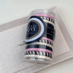 Close-up of high elasticity hand-woven hair ties in a clear storage cylinder tube